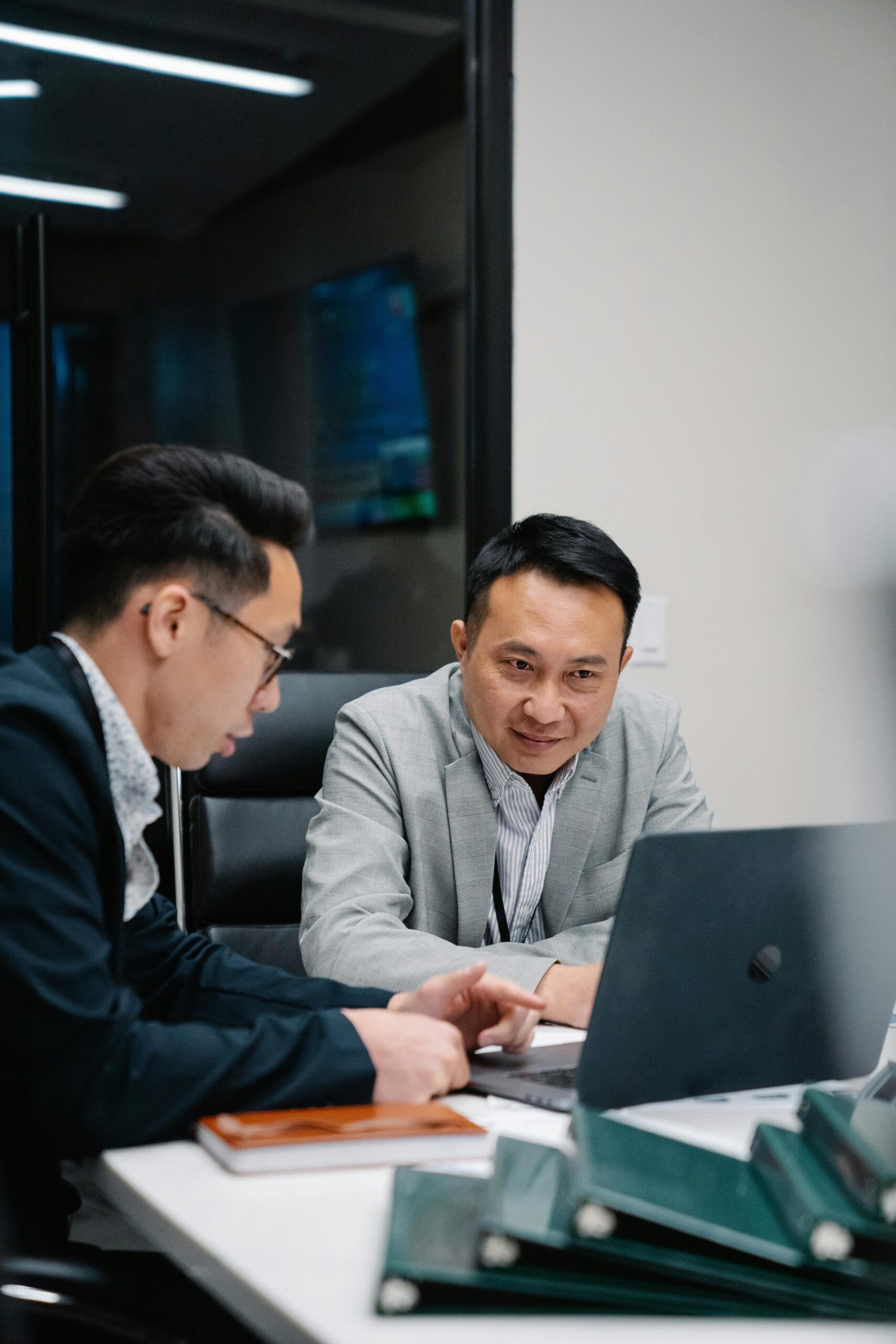 Two men looking at a computer and writing notes
