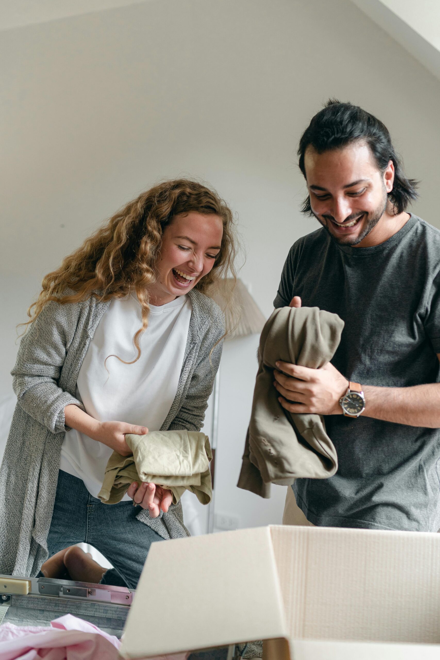 Young couple putting their clothes in a box to move house